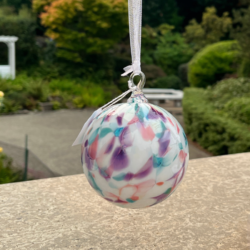 hand blown glass ornament with pink, green, blue design on white background