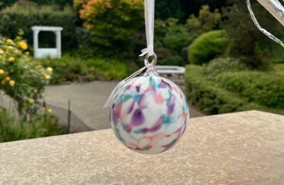 hand blown glass ornament with pink, green, blue design on white background